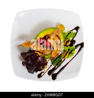 Vue de dessus des quartiers de jambes de caille grillées servis sur une assiette blanche avec des légumes, des baies et de la pâte balsamique. Isolé sur fond blanc . Banque D'Images