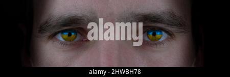 Gros plan du visage masculin avec des yeux jaunes bleus. Symbole du patriotisme du peuple ukrainien. Bannière Banque D'Images