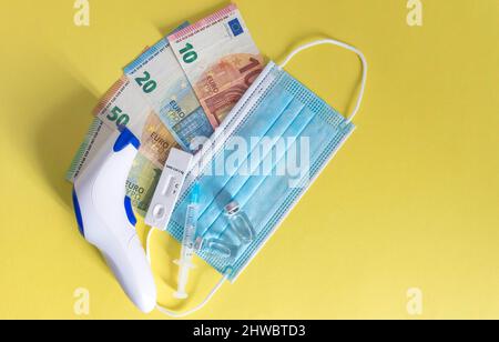 Argent (billets en euros) avec masques médicaux, test d'antigène, flacons de vaccins et seringue. Crise financière due aux pertes du coronavirus, sélectif f Banque D'Images