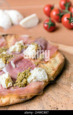 Pizza italienne sur planche à découper en bois. Sur fond flou, tomates cerises et mozzarella. Banque D'Images