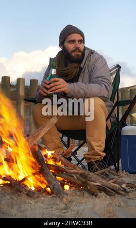 Chauffe après une longue journée. Deux jeunes hommes assis autour d'un feu sur la plage. Banque D'Images