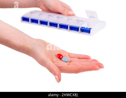 Femme mains prenant des pilules de l'organisateur isolé sur fond blanc. Concept de soins de santé. Photo de haute qualité Banque D'Images