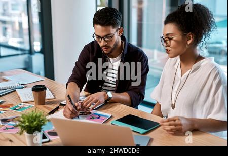 Marquons celle-ci pour ne pas l'oublier. Plan court de deux jeunes hommes d'affaires assis ensemble et ayant une réunion sur les polaroïdes dans le bureau. Banque D'Images