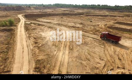 Le camion roule sur une route de carrière de sable.Scène.Vue de dessus de la conduite d'un camion-benne sur une route jaune en terre dans la campagne.Gros camions sur des chantiers de construction ou de carrière Banque D'Images