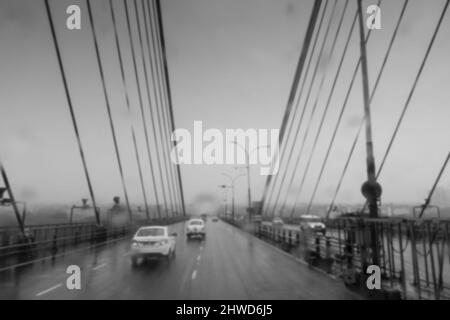 Image floue, image prise à travers des gouttes tombant sur le pare-brise de voiture, verre humide, la circulation à 2nd Hoogly Bridge. Image Monsoon en noir et blanc. Banque D'Images