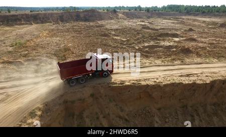 Décharger le camion sur la route rurale.Scène.Vue de dessus des trajets en camion, laissant des panaches de poussière dans la route de terre en campagne, dans le contexte de la carrière de pelle hydraulique Banque D'Images