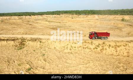 Décharger le camion sur la route rurale.Scène.Vue de dessus des trajets en camion, laissant des panaches de poussière dans la route de terre en campagne, dans le contexte de la carrière de pelle hydraulique Banque D'Images