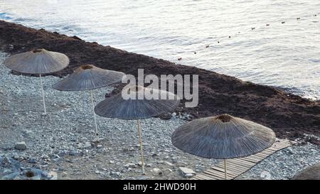 Vue de dessus de jour ensoleillé à la plage avec une crue de soleil de paille. Paysage d'été avec plage de galets et parasols pour la protection contre le soleil. Banque D'Images