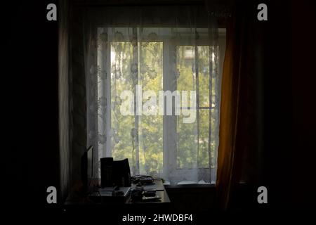 Fenêtre dans la chambre. Appartement en Russie. Rideaux sur la fenêtre. Chambre sombre. Banque D'Images