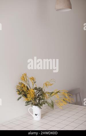 Composition des fleurs de printemps. Fleurs de mimosa jaunes sur fond blanc à l'intérieur de la maison. Banque D'Images