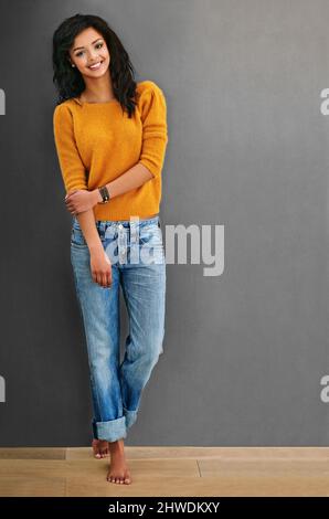 C'est les choses simples dans la vie qui me font sourire. Photo en studio d'une jeune femme attrayante posant sur un fond gris. Banque D'Images