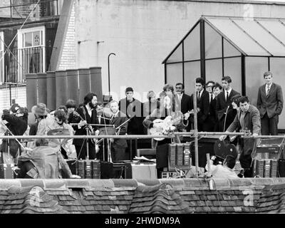 Les Beatles exécutent un concert sur le toit au siège d'Apple, 3 Saville Row Londres, le 30th janvier 1969. La représentation faisait partie du tournage d'un documentaire du groupe qui répète et enregistre l'album Laissez-le être. La session de 42 minutes a attiré la foule vers la rue et les toits adjacents. Il s'agissait de la dernière représentation en direct du groupe avant sa rupture en avril 1970. En haut de la rue, de gauche à droite : Ringo Starr, Paul McCartney, John Lennon et George Harrison. Banque D'Images