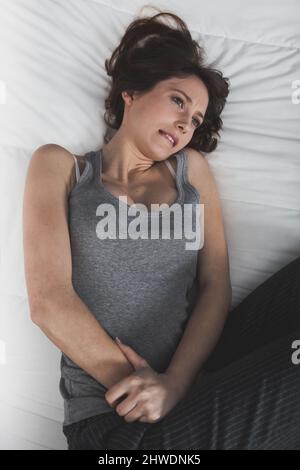 Portrait d'une jeune femme en douleur avec PMS, syndrome prémenstural Banque D'Images