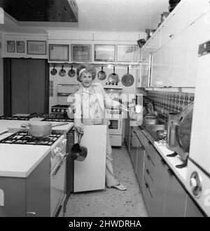 Johnnie et Fanny Cradock, l'expert en cuisine télévisuelle, ont déménagé dans une nouvelle maison près de Watford, dans le Hertfordshire. La maison elle-même était à l'origine un chalet de 18th siècle qui au fil des ans a été construit sur, en maintenant le plus près possible de la façade d'origine. L'intérieur a été complètement fait par les Cradock's avec tous les inconvénients modernes habituels, y compris une grande cuisine contenant six poêles à gaz., dans laquelle ils instruire une petite équipe de jeunes qui les aident dans leurs émissions de télévision. Fanny démontre la disposition facile de la cuisine - du poêle à gaz à l'évier. 9th juin 1969. Banque D'Images