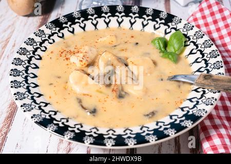 Une soupe de poulet et de champignons maison ou un fricassée de poulet à la française, dans un bol à soupe sur une table en bois. Vue en hauteur. Banque D'Images
