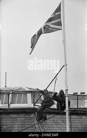 Deux hommes en kit de mountaineers ont grimpé le mât sur la Rhodésie House à minuit le 11th janvier - ils ont descendu le drapeau de Rhodésie, l'ont remplacé par l'Union Jack et ont dit aux policiers qui ont essayé des descendre, Ils restaient mis jusqu'à la manifestation de l'après-midi le 12th janvier à l'extérieur de la maison de Rhodésie. A 10am ans, ils avaient des sandwiches alors qu'ils étaient encore sur le mât et ensuite l'un d'eux a lu un livre. 12th janvier 1969. Banque D'Images