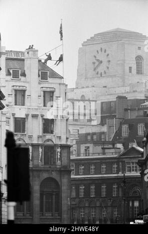 Deux hommes en kit de mountaineers ont grimpé le mât sur la Rhodésie House à minuit le 11th janvier - ils ont descendu le drapeau de Rhodésie, l'ont remplacé par l'Union Jack et ont dit aux policiers qui ont essayé des descendre, Ils restaient mis jusqu'à la manifestation de l'après-midi le 12th janvier à l'extérieur de la maison de Rhodésie. A 10am ans, ils avaient des sandwiches alors qu'ils étaient encore sur le mât et ensuite l'un d'eux a lu un livre. 12th janvier 1969. Banque D'Images