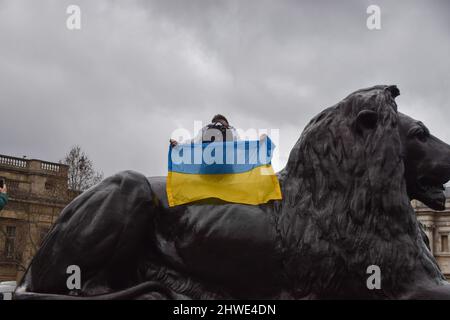 Londres, Royaume-Uni. 5th mars 2022. Un manifestant est assis sur une statue de lion avec un drapeau ukrainien. Des milliers de personnes se sont rassemblées sur Trafalgar Square pour le onzième jour des manifestations, alors que l'attaque russe sur l'Ukraine se poursuit. Credit: Vuk Valcic/Alamy Live News Banque D'Images