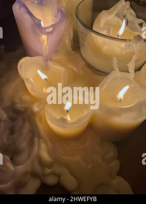 plusieurs bougies allumées se tiennent sur une table dans un intérieur sombre, la cire fondue autour des bougies, vue à angle élevé Banque D'Images