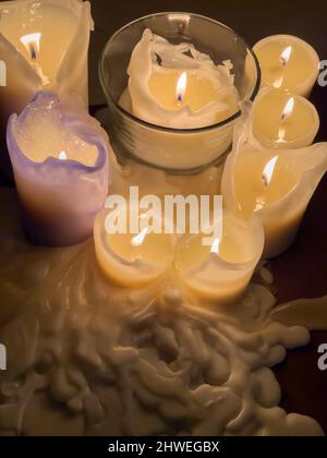 plusieurs bougies allumées se tiennent sur une table dans un intérieur sombre, la cire fondue autour des bougies, vue à angle élevé Banque D'Images