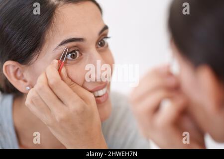 Se débarrasser des poils indésirables. Une jeune femme qui bruitait ses sourcils. Banque D'Images