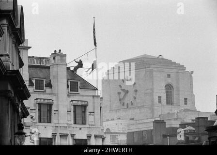 Deux hommes en kit de mountaineers ont grimpé le mât sur la Rhodésie House à minuit le 11th janvier - ils ont descendu le drapeau de Rhodésie, l'ont remplacé par l'Union Jack et ont dit aux policiers qui ont essayé des descendre, Ils restaient mis jusqu'à la manifestation de l'après-midi le 12th janvier à l'extérieur de la maison de Rhodésie. A 10am ans, ils avaient des sandwiches alors qu'ils étaient encore sur le mât et ensuite l'un d'eux a lu un livre. 12th janvier 1969. Banque D'Images