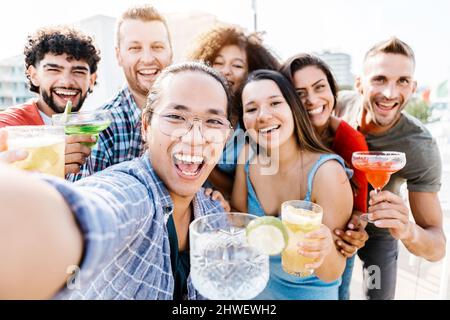 De jeunes amis prennent le selfie avec le téléphone tout en buvant des cocktails branchés Banque D'Images