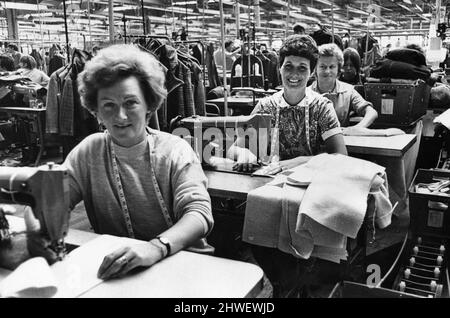 Les mamans machinistes qui travaillent continuent à produire à l'usine de robes de Steingberg et de fils de Hawthorn, Pontypridd, tandis que leurs enfants s'occupaient de la garderie voisine dans une salle de classe de l'école secondaire du comté de Hawthorn. Des superviseurs formés ont été payés par l'entreprise pour s'occuper de la classe de vacances scolaires de 25 garçons et filles âgés de cinq à dix ans. 20th août 1969. Banque D'Images