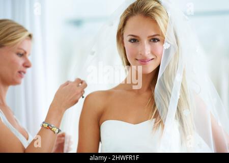 En mettant les touches finales. Une jeune femme essayant de robes de mariage dans une boutique de mariée. Banque D'Images