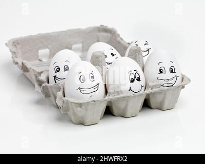 Des œufs heureux font des aliments sains. Studio photo de visages dessinés sur une boîte d'oeufs. Banque D'Images