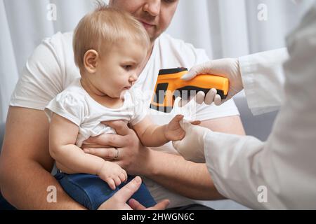 Médecin vérifiant la température du bébé à l'aide d'un thermomètre infrarouge Banque D'Images