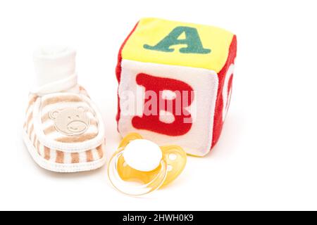 concept enfant avec bottes, sucette et cube en peluche pour nouveau-né sur fond blanc Banque D'Images