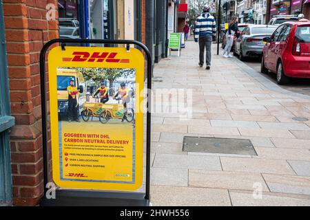 DHL signe ou A-board annonçant leur Go Green avec DHL Carbon neutre livraison plan, Camberley High Street, Surrey, Royaume-Uni Banque D'Images