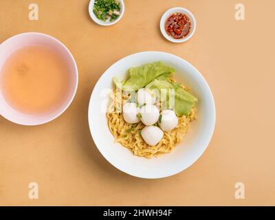 Délicieux plats thaïlandais boule de poisson dans un bol avec soupe, sauce Chili et oignon de printemps vue sur une table en bois Banque D'Images