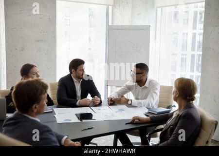 Groupe de gens d'affaires multiraciaux heureux concentrés discutant de la stratégie. Banque D'Images