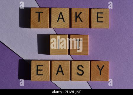 Prenez-le facilement, les mots en lettres de l'alphabet de bois isolées sur fond violet Banque D'Images