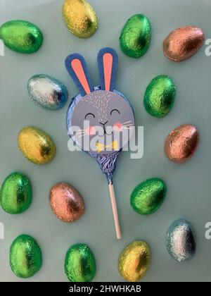 Le petit-pain de Pâques en forme de lapin est entouré d'œufs de chocolat enveloppés de papier aluminium Banque D'Images