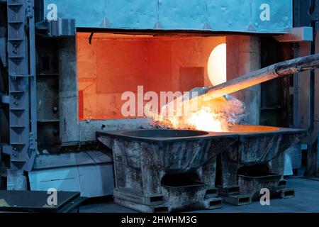 L'écrémage aluminium fondu pour enlever les scories avant moulage. Fonderie aluminium works montrant un four ouvert Banque D'Images