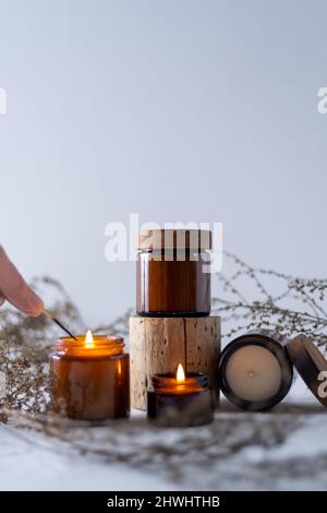 Un ensemble de bougies de soja dans un pot en verre brun avec un couvercle en bois. Bougie aromatique brûlante. Des bougies lumineuses avec un match. Confortable et agréable. Aromathérapie. Banque D'Images