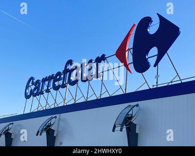 Liège, Belgique - Mars 3. 2022: Vue sur le logo du supermarché carrefour au-dessus de l'entrée du magasin, dans un ciel bleu clair Banque D'Images