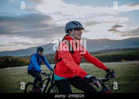 Couple senior actif à vélo en plein air dans la forêt en automne. Banque D'Images