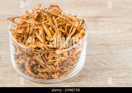 Le cordyceps militaris séché fleur de champignon sur fond de bois. Banque D'Images