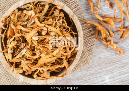 Le cordyceps militaris séché fleur de champignon sur fond de bois. Banque D'Images