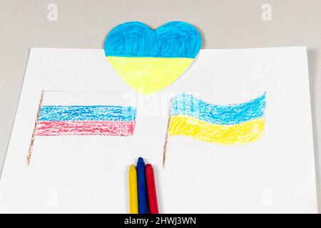 Gros plan sur les drapeaux de l'Ukraine et de la Russie et un coeur aux couleurs jaune-bleu. Enfants pour la paix. Les enfants dessinant pour la paix dans Banque D'Images