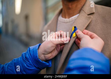 Organisateur de manifestations distribuant des rubans bleus et jaunes ukrainiens aux personnes protestant contre la guerre en Ukraine Banque D'Images