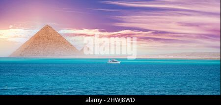 Coucher de soleil mer rouge avec yacht blanc fond pyramide égyptienne le Caire, Egypte. Banque D'Images