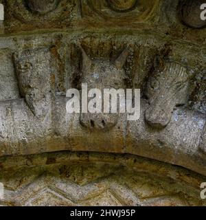 Des têtes médiévales, représentant des bêtes mythiques, des oiseaux et même des visages humains, se trouvent à proximité de l'arche ronde, au-dessus de la porte sud de l'église paroissiale Saint-Sin du début du 12th siècle à Quenington, Gloucestershire, Angleterre, Royaume-Uni. La sculpture normande extravagant - que l'on trouve en Angleterre, en Irlande, en France et en Espagne - a peut-être représenté les péchés et les vices du monde laissés pour compte lorsque les fidèles sont entrés dans les églises. Banque D'Images