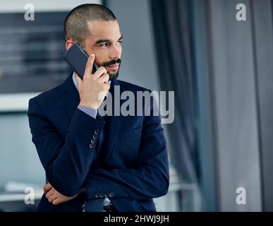 Dites-moi ce que je veux entendre Photo d'un jeune homme d'affaires parlant sur un téléphone portable dans son bureau. Banque D'Images