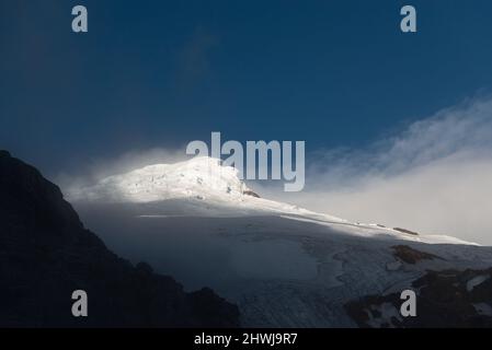 Pic et glacier du volcan Cayambe au coucher du soleil avec brume, parc national Cayambe Coca, Équateur. Banque D'Images