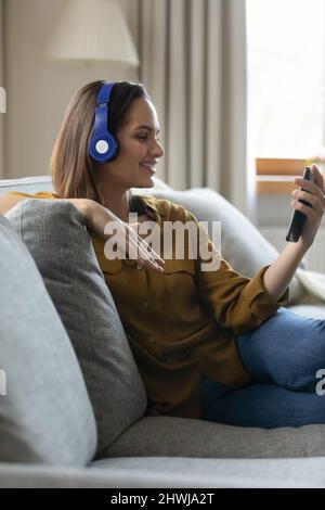 Femme souriante porte un casque tient le smartphone regarder le clip vidéo Banque D'Images